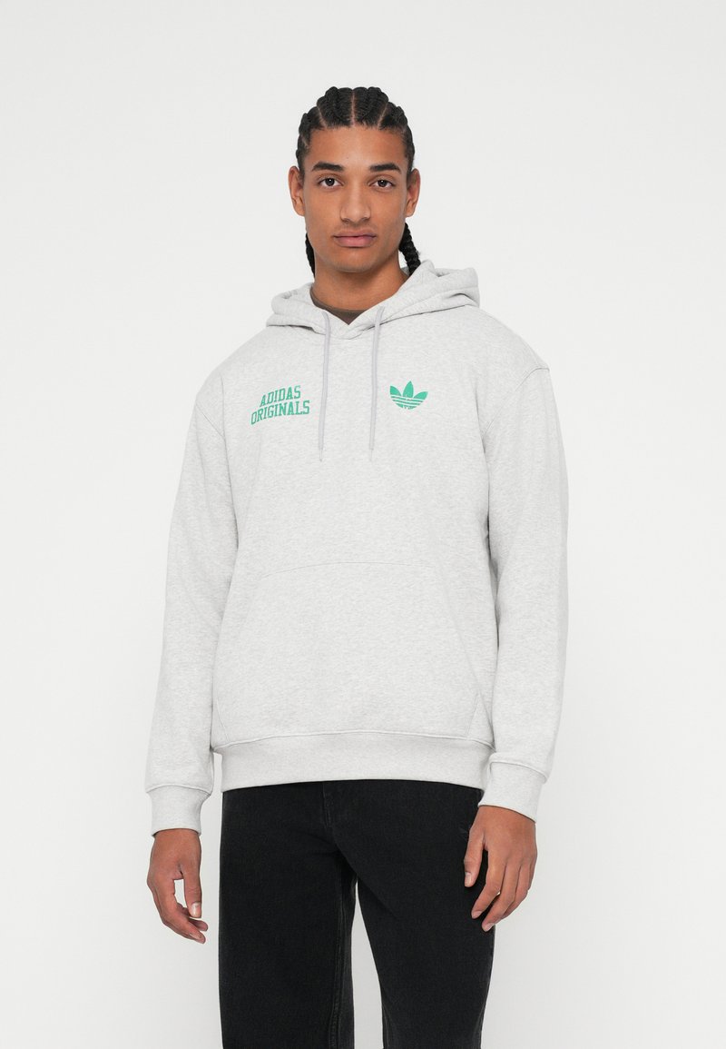 Szary pulower z kapturem wykonany z miękkiego materiału, z kieszenią typu kangur, kapturem ze sznurkiem oraz zielonym logo "Adidas Originals" na piersi.