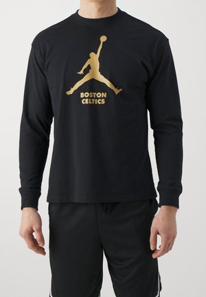 Homme portant un t-shirt noir à manches longues avec la silhouette dorée d'un joueur de basketball tendant la main vers le haut, texte « BOSTON CELTICS » en dessous.