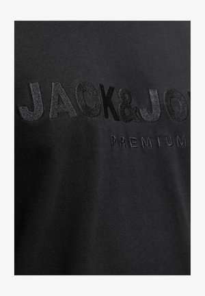 Juodas medvilnės marškinėliai su iškilniu juodu siuvinėjimu, kuriame užrašyta "JACK&JONES PREMIUM." Sklandus audinys ir prigludęs dizainas.