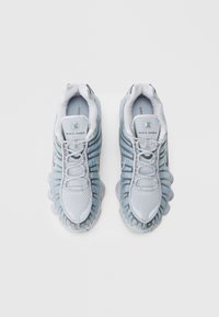 Ανοιχτό μπλε και γκ�ρι αθλητικά παπούτσια Nike Shox με ύφασμα από δίχτυ και πλαστικές λεπτομέρειες. Διαθέτουν χαρακτηριστική σόλα με αποσβεστήρες κολώνες και κορδόνια.