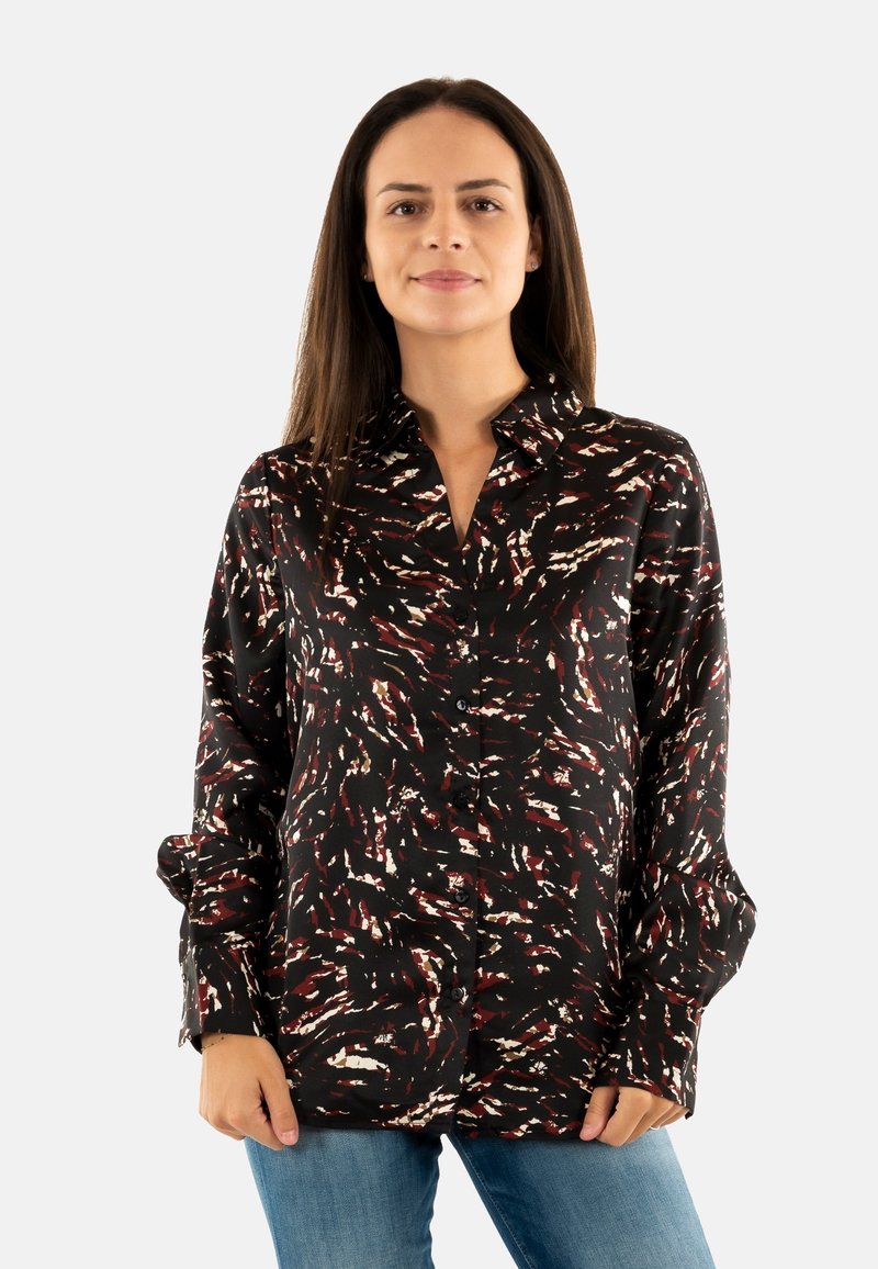Camisa de manga larga, abotonada, en tela negra con un patrón en espiral de rojo y blanco. Presenta un cuello clásico y un corte relajado.