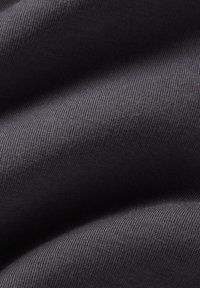 Svart ribbat tyg med en mjuk textur, som visar en subtil lyster och vågliknande veck. Ytan har ett enhetligt, fint mönster.