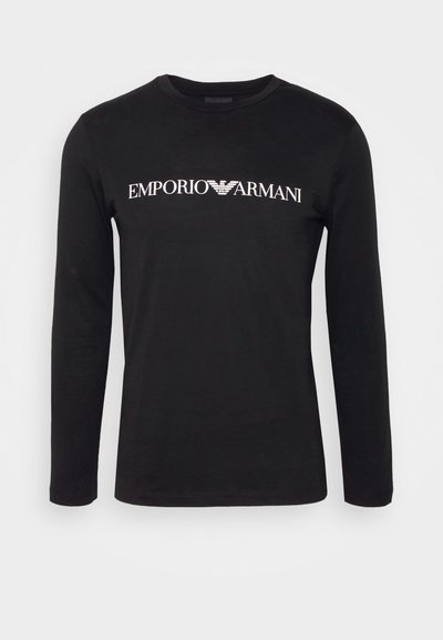 Crna majica dugih rukava od pamuka, s bijelim logotipom "EMPORIO ARMANI" preko prsa. Glatka tekstura sa klasičnim okruglim izrezom.