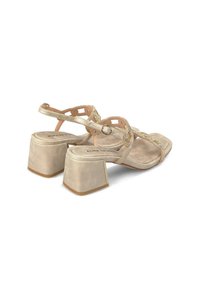 Beige hakken sandalen met een blokhak, decoratieve banden met uitsparingspatronen en strass-detail op de bovenkant.