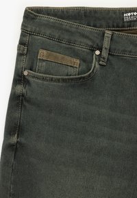 Jeans de mezclilla verde oscuro con un diseño clásico de cinco bolsillos, que presentan herrajes de latón y costuras en contraste a lo largo de las costuras.