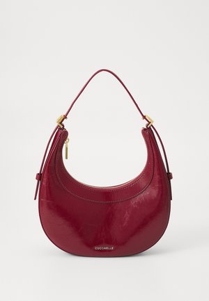 Sac à main en cuir rouge avec une silhouette incurvée. Doté d'une poignée supérieure, de quincaillerie dorée et de détails de couture visibles. Fermeture par zip.