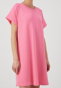 Vestido t-shirt oversized rosa con mangas cortas, escote redondo, hecho de una tela suave, presenta un dobladillo recto y un diseño minimalista.