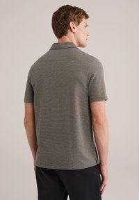 Polo gris de manga corta con tejido texturizado, cuello clásico y detalle de abertura lateral, usado por un modelo visto desde atrás.