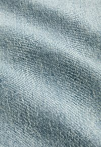 Lichtblauwe denimstof met een gestructureerde weving en een subtiel verloop. Het oppervlak vertoont lichte variaties en heeft een zachte afwerking.