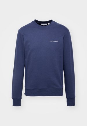 Sudadera de cuello redondo en azul marino, hecha de algodón, con mangas largas y un pequeño texto de logo blanco en el pecho. Textura suave, ajuste casual.