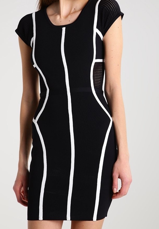 Femme portant une robe noire ajustée à manches courtes avec des rayures blanches verticales et courbes soulignant la silhouette.