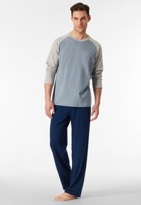 Camicia a maniche lunghe azzurro chiaro con maniche grigie e pantaloni blu navy. Il tessuto sembra morbido con una vestibilità comoda. La camicia presenta un collo rotondo.