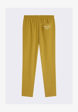 Pantalones amarillos tejidos con un acabado texturizado, que cuentan con una cinturilla elástica y un único bolsillo trasero con detalles en texto blanco.