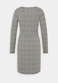 Robe à manches longues avec une silhouette cintrée, en motif à carreaux noir et blanc, dotée d'un col rond et d'une longueur mi-cuisse.