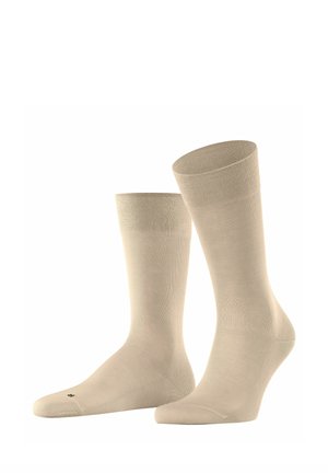 Beige Baumwollsocken mit glatter Textur, mittellanger Länge bis zur Wade und geripptem Bündchen, mit minimalistischem Design und kleinem Logo auf der Sohle.