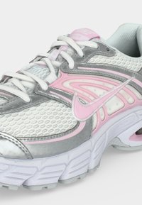 Λευκό και ροζ αθλητικό παπούτσι Nike με ασημί λεπτομέρειες, διχτυωτό επάνω μέρος, μαξιλαρωμένη σόλα και λευκές κορδονόδεσμες.