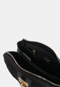 Borsa nera realizzata in pelle texturizzata con hardware dorato, dotata di chiusura con zip e numerose tasche interne per l'organizzazione.