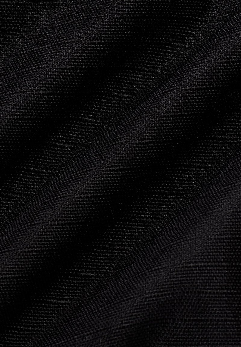 Inquadratura ravvicinata di un tessuto nero a trama fitta che mostra una texture dettagliata e pieghe sottili in un materiale morbido.