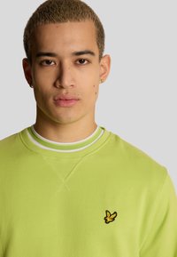 Felpa verde neon con scollatura rotonda, dettagli bianchi e logo ricamato. Tessuto morbido con una vestibilità comoda.