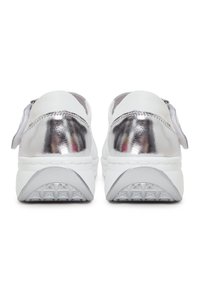 White sneakers with metallic silver accents at the heel, textured rubber sole, and stitch detailing. Slip-on design with a soft lining.