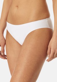 Białe bikini z gładką fakturą. Posiada niską talię i bezszwową talię, podkreślającą prostotę i wygodę.