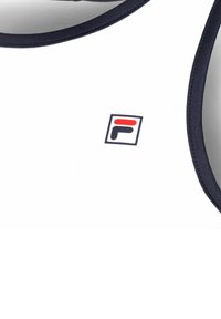 Top atletico bianco senza maniche con rifiniture navy e un piccolo logo FILA rosso e navy sul petto.