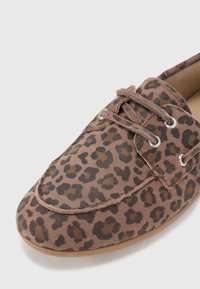 Sko med leopardmønster i mykt stoff og rund tå. Har snøring, sølvfargede hull og en brun såle. Teksturert, detaljert mønster gjennom hele skoen.