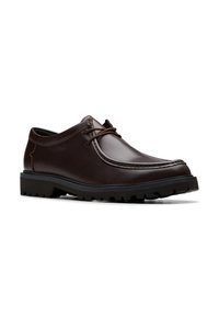 Chaussure en cuir marron à lacets avec une finition lisse, bout arrondi, semelle en caoutchouc noire contrastante et détails cousus le long de la tige.