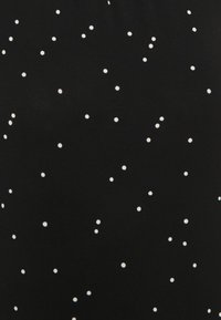 Czarna tkanina w białe kropki, charakteryzująca się gładką fakturą. Wzór jest równomiernie rozłożony po powierzchni.