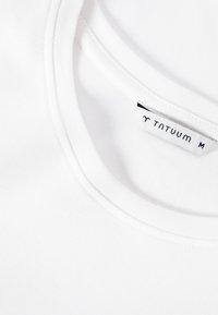 Λευκό T-shirt με στρογγυλή λαιμόκοψη και ορατή εσωτερική ετικέτα που δείχνει το όνομα της μάρκας "TNTUUM" και το μέγεθος "M" στη λαιμόκοψη.