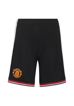 Pige og dreng iført Manchester Uniteds røde fodboldtrøjer, sorte shorts, sokker og hvide fodboldstøvler, stående side om side.