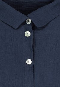 Navy blue button-up shirt with a soft texture, featuring a classic collar and four metallic buttons with round, flat surfaces.