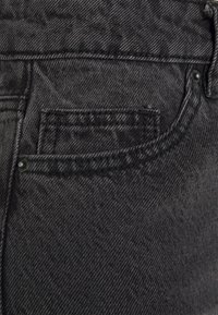 Jeans de ganga pretos com uma textura suave, design clássico de bolsos e costura contrastante ao longo das costuras e bordas.
