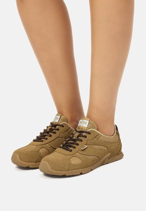 Zapatillas de malla y cuero ante marrón con cordones negros, suelas de goma marrón claro y logotipo en la lengüeta. Diseño bajo para uso casual.