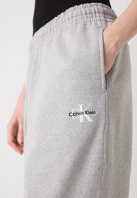 Grijze katoenen joggingbroek met een elastische tailleband en zijzak. Voorzien van een bedrukte Calvin Klein-logo in zwart-wit op de bovenbeen.