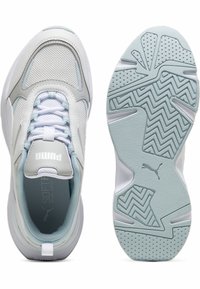 Chaussures de sport blanches et bleu clair avec une tige en mesh et synthétique, dotées d'une semelle texturée à motif en zigzag et d'un logo sur la languette.