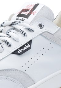 White leather sneaker with grey suede accents, perforated detail, black logo patch, and patterned laces. Tag reads "MAKE SHEDS WITH LOVE."