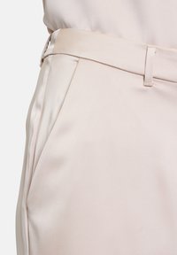 Beige Satin-Hosen mit glatter Textur und taillierter Passform. Verfügen über einen schmalen Bund und seitliche Taschen für zusätzliche Funktionalität.