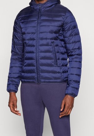 Giacca puffo blu navy con cappuccio, texture trapuntata, zip frontale e tasche laterali. Presenta polsini elasticizzati e un design aderente.