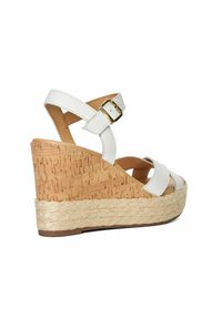 White leather wedge sandal with cork and jute base. Cross strap design, adjustable ankle strap with gold buckle, textured surface.