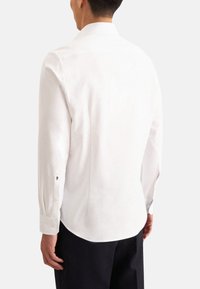 Witte lange mouwen shirt met een puntige kraag, geknoopte manchetten en een gladde textuur, van achteren gezien. De pasvorm is op maat en comfortabel.