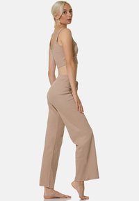 Top court ajusté beige à larges bretelles associé à un pantalon ample taille haute. Texture douce avec un motif côtelé.