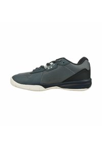 Zapatilla deportiva gris con parte superior de malla, puntera redondeada y suela de goma blanca con acentos negros. Detalles texturizados en el lateral y la lengua.