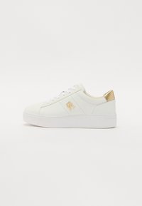 Baskets en cuir blanc avec une texture lisse, accent doré sur le talon, semelles blanches et lacets blancs. Présente un logo sur le côté.