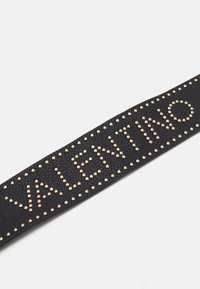 Black leather strap with gold studs, featuring "VALENTINO" text in bold studded lettering. The surface has a textured finish.