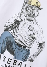 Biała koszulka z grafiką tygrysa w stroju baseballowym, trzymającego kij, w niebieskich spodniach i żółtej czapce. Szczegółowo zdobiona wzorami i akcentami.