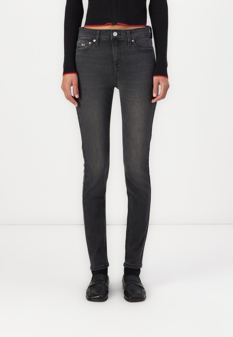 Černé skinny džíny s vybledlým vzhledem, které mají pět kapsičkový design a stříbrné doplňky. Kombinováno s černým pleteným topem a černou obuví.