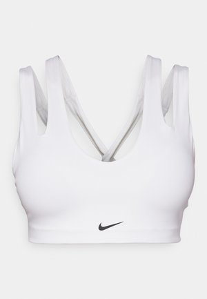 White sports bra featuring a scoop neckline, thick straps, and crisscross back design. Nike logo in black at the center front. Smooth texture.