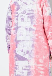 Sudadera oversized de tie-dye en rosa y morado. Presenta grandes letras blancas que dicen "HAPPY". Tejido suave y texturizado con un corte relajado.