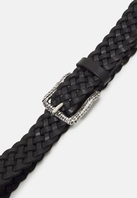 Cinturón de cuero trenzado negro con hebilla plateada texturizada. El diseño es plano y cuenta con un lazo de cierre ajustable.